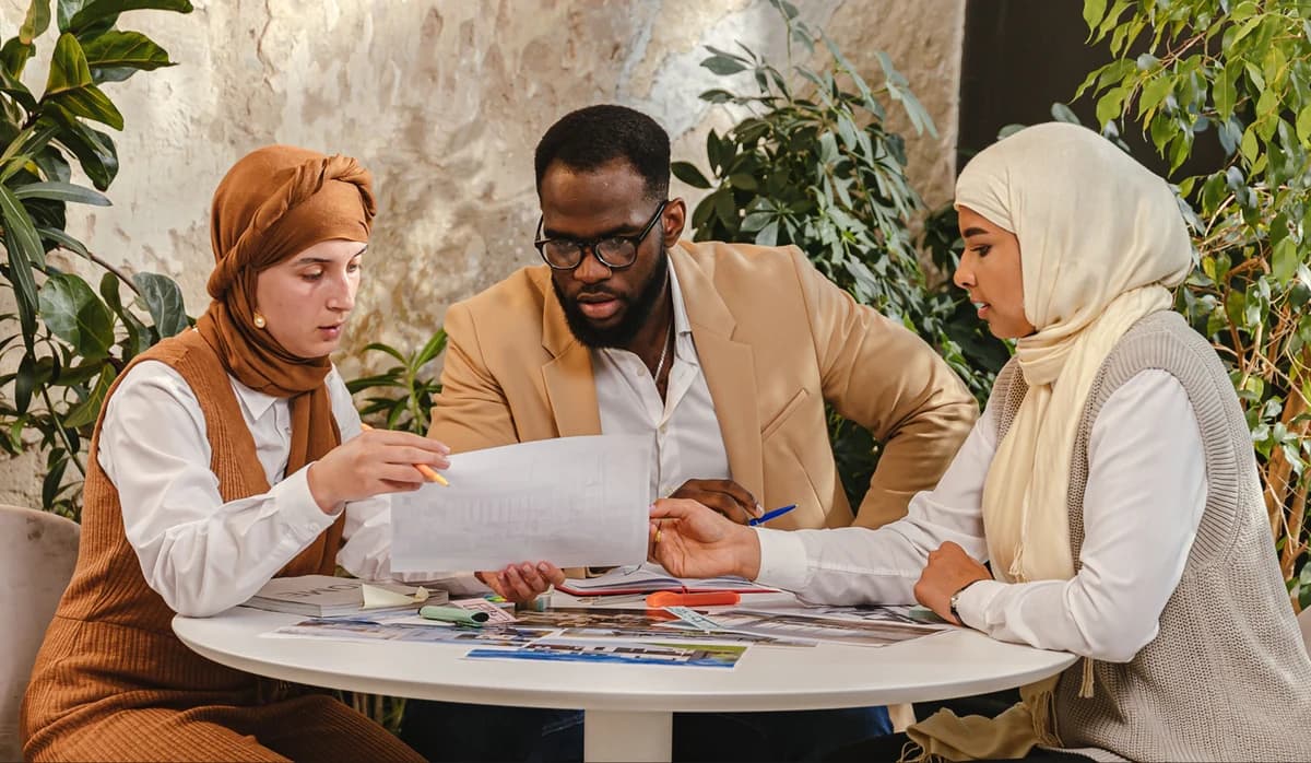 Three colleagues reviewing printed charts around a cafe table