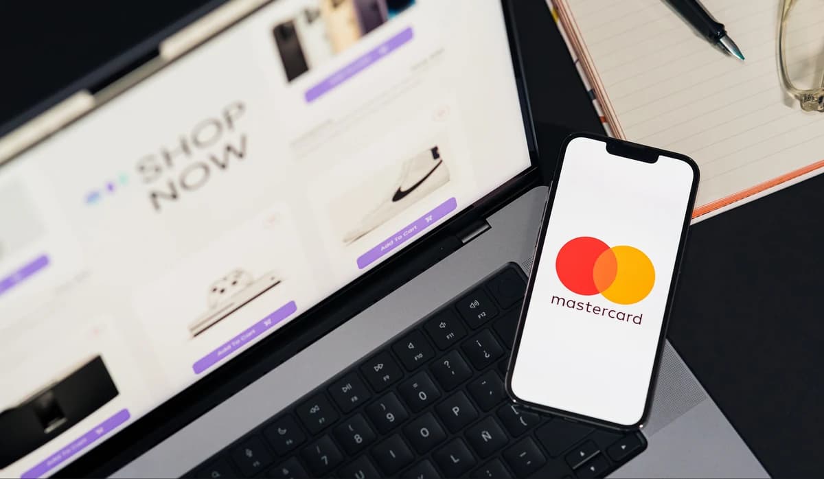 A phone showing a card payment resting against a laptop on a storefront checkout