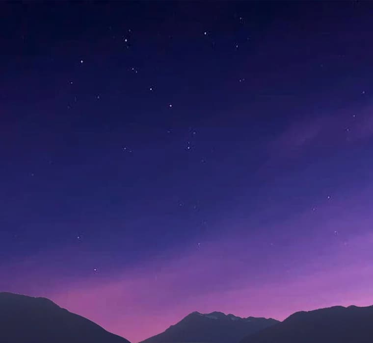 Star-filled violet night sky above a mountain ridge